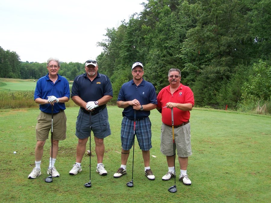 Four golfers posing together on the fairway.